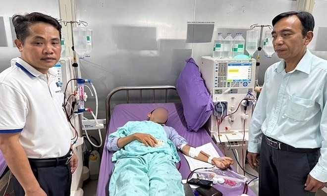 Giám đốc BHXH huyện Mỹ Xuyên và lãnh đạo Bệnh viện Đa khoa Hoàng Tuấn thăm hỏi sức khỏe ông L.Q.N. Ảnh: Lao động