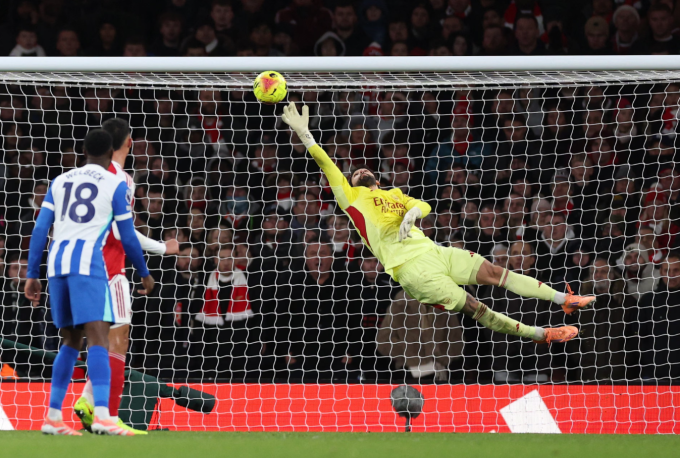 David Raya bay người cản cú đá của Yankuba Minteh. Ảnh: Reuters