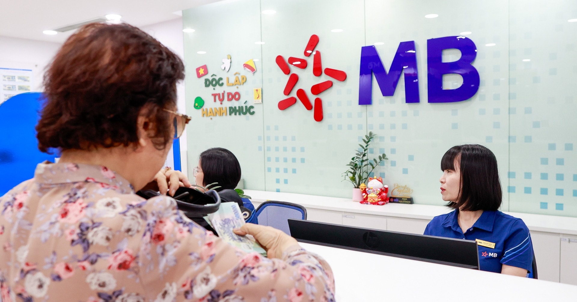 Nhân viên ngân hàng thực hiện giao dịch cho khách hàng tại quầy trong ngày MB tăng lãi suất