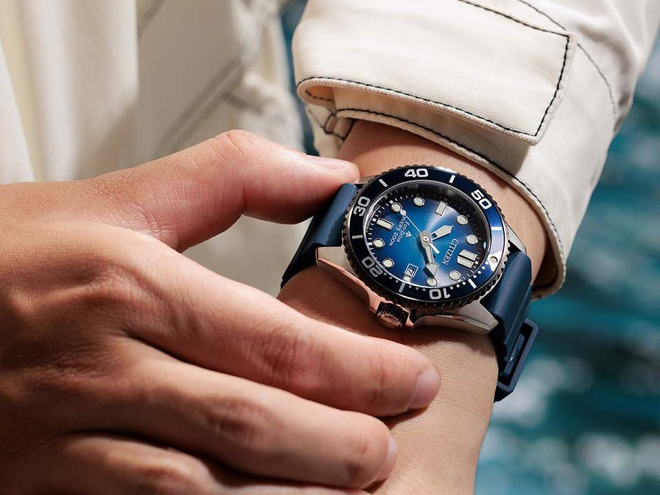 Người đeo Citizen Promaster Marine BN0267-04L với mặt số chuyển sắc xanh và dây xanh trên cổ tay.
