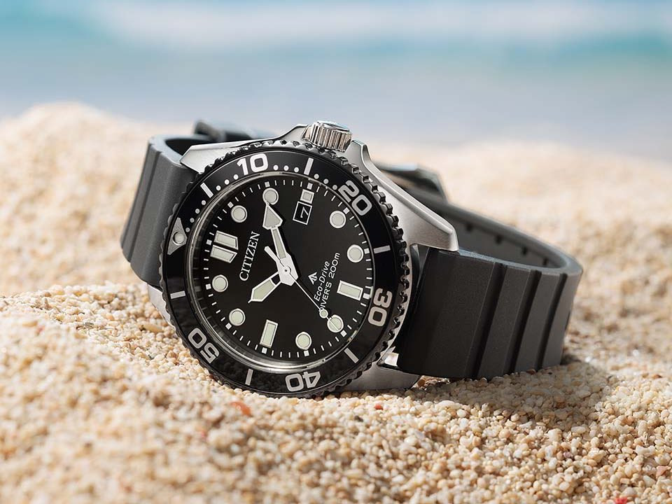 Citizen Promaster Marine BN0266-07E với mặt số đen, bezel đen và dây đen đặt trên cát.