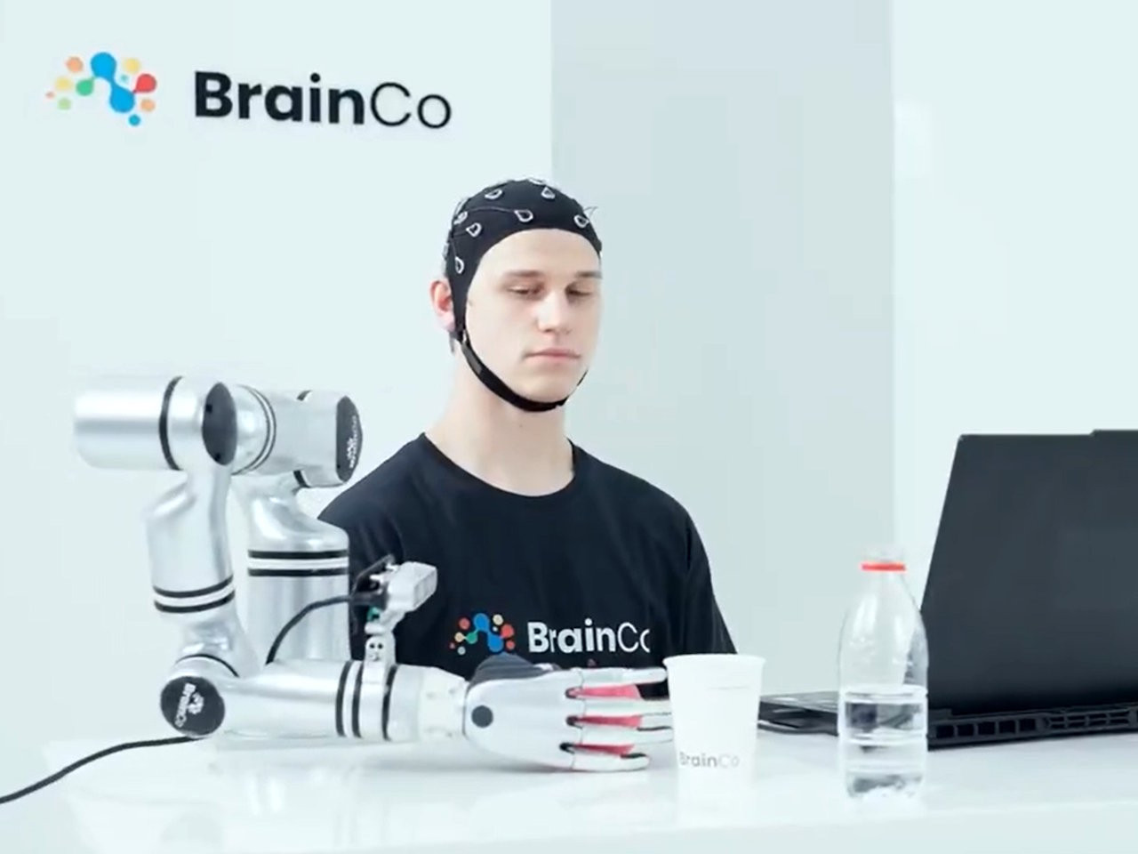 Người dùng công nghệ điều khiển bằng ý nghĩ của BrainCo đang điều khiển robot lấy một quả táo.